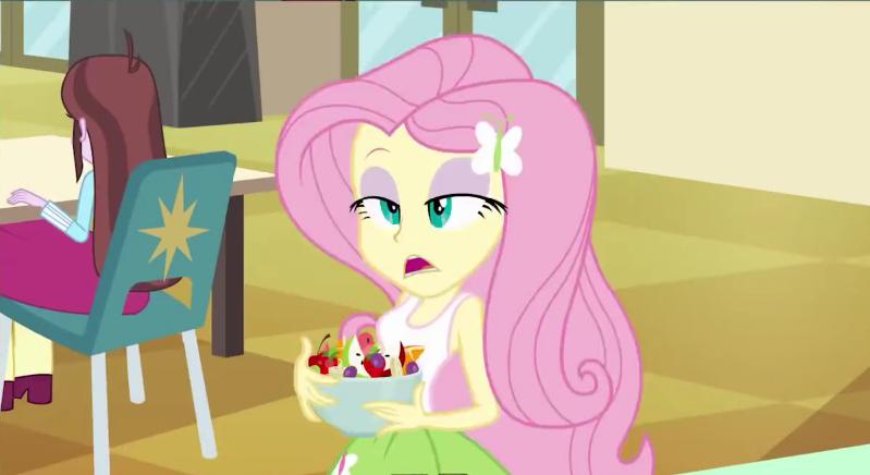 Size: 799x436 | Tagged: safe, derpibooru import, screencap, fluttershy, velvet sky, equestria girls, apple, background human, bowl, cherry, cross-eyed, eyeshadow, food, frown, fruit salad, grapes, hair ornament, lidded eyes, makeup, open mouth, orange, salad, solo focus