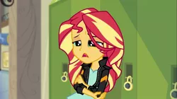 Size: 1100x618 | Tagged: safe, derpibooru import, screencap, sunset shimmer, equestria girls, friendship games, clothes, hand on arm, hand on elbow, jacket, leather jacket, lockers, solo