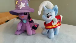 Size: 1328x747 | Tagged: artist needed, source needed, useless source url, safe, derpibooru import, trixie, twilight sparkle, pony, unicorn, 4de, cape, clothes, female, hat, irl, mare, photo, plushie, swap, trixie's cape, trixie's hat, wells fargo