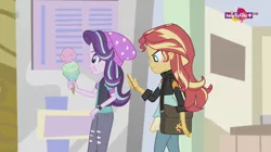 Size: 1136x638 | Tagged: safe, derpibooru import, screencap, starlight glimmer, sunset shimmer, equestria girls, mirror magic, spoiler:eqg specials, beanie, canterlot mall, female, food, geode of empathy, hat, ice cream, magical geodes, mobile phone, phone, teletoon