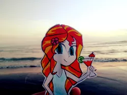 Size: 950x713 | Tagged: safe, artist:daniel-phoenixd, derpibooru import, sunset shimmer, pony, beach, drinking, hulashimmer, human coloration, irl, ocean, paper child, photo, smiling, solo