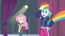 Size: 1280x718 | Tagged: safe, derpibooru import, screencap, fluttershy, rainbow dash, dance magic, equestria girls, spoiler:eqg specials, arm behind head, backwards ballcap, baseball cap, cap, clothes, confused, hat, head scratch, hip hop, open mouth, outfit, pants, rapper dash, stage