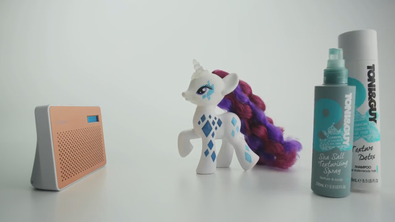 Size: 1366x768 | Tagged: safe, derpibooru import, rarity, pony, unicorn, brushable, commercial, cutie mark magic, glamor glow rarity, hair spray, irl, live action, merchandise, photo, pop culture, radio, solo, toy, very, very (uk store)