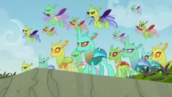 Size: 1280x720 | Tagged: background changeling, big damn heroes, changedling, changeling, changeling swarm, cliff, clypeus, cornicle, derpibooru import, discovery family logo, flying, grass, safe, screencap, to change a changeling