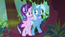 Size: 1280x720 | Tagged: safe, derpibooru import, screencap, starlight glimmer, trixie, pony, unicorn, road to friendship, arm around neck, bipedal, duo, female, hoof around neck, hooves on hips, looking at each other, mare, open mouth, smiling, standing, swamp, tree, we're friendship bound