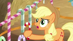 Size: 1280x720 | Tagged: safe, derpibooru import, screencap, applejack, earth pony, pony, the great escape room, candy, candy cane, female, food, freckles, hay, holding, mare, solo