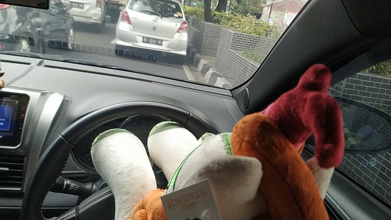 Size: 1280x720 | Tagged: artist:burgunzik, autumn blaze, behind, car, derpibooru import, female, indonesia, irl, kirin, photo, plushie, raised hoof, safe, solo, sounds of silence, steering wheel