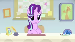 Size: 1280x720 | Tagged: safe, derpibooru import, screencap, starlight glimmer, pony, unicorn, starlight the hypnotist, spoiler:interseason shorts, cute, desk, glimmerbetes, guidance counselor, hair flip, hair over one eye, sitting, smiling, solo, starlight's office