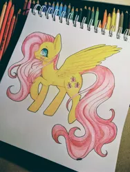 Size: 3120x4160 | Tagged: safe, artist:hikarinohibana, derpibooru import, fluttershy, pegasus, pony, blushing, colored pencil drawing, female, mare, pencil, photo, profile, raised hoof, raised leg, sketchpad, smiling, solo, spread wings, standing, traditional art, wings