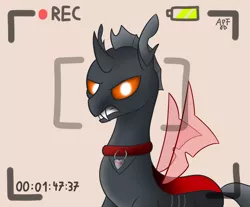 Size: 1024x846 | Tagged: angry, artist:atomfliege, camera, camera shot, changeling, changeling oc, collar, derpibooru import, looking at you, oc, oc:dragi, recording, red changeling, safe, simple background, solo, teeth, unofficial characters only