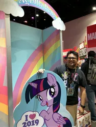 Size: 3024x4032 | Tagged: 2019, alicorn, derpibooru import, eyeshadow, hasbro, human, irl, makeup, male, minge, mlp g1 logo, photo, safe, sdcc 2019, smiling, standee, twilight sparkle, twilight sparkle (alicorn), waifu