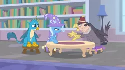 Size: 1600x900 | Tagged: safe, derpibooru import, screencap, gallus, grampa gruff, trixie, gryphon, pony, unicorn, a horse shoe-in, blind eye, book, bookshelf, cape, carpet, clothes, complaining, female, fez, hat, lamp, male, mare, sad, sitting, stool, table, teenager, trixie's cape, trixie's hat, upset