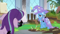 Size: 1600x900 | Tagged: safe, derpibooru import, screencap, starlight glimmer, trixie, pony, a horse shoe-in, bog, burnt, cape, cattails, clothes, column, dirt, easel, grass, hat, inkwell, leaves, mess, moss, quill, singed, trixie's cape, trixie's hat, window