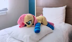 Size: 1280x746 | Tagged: artist:dawning love, artist:natureshy, bed, clothes, derpibooru import, fluttershy, heart eyes, irl, laying on bed, laying on pillows, on bed, photo, plushie, safe, socks, solo, striped socks, wingding eyes