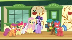 Size: 1366x768 | Tagged: safe, derpibooru import, screencap, biscuit, fluttershy, spur, twilight sparkle, twilight sparkle (alicorn), alicorn, pony, growing up is hard to do, bag, box, chest, cmc safe, disappointed, door, neckerchief, ribbon, saddle bag, smiling, squint, train station, unamused, window