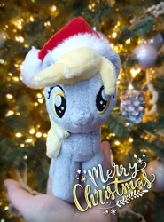 Size: 1000x1352 | Tagged: safe, artist:meplushyou, derpibooru import, derpy hooves, pegasus, pony, background pony, christmas, christmas tree, hand, holding a pony, holiday, irl, photo, plushie, tree