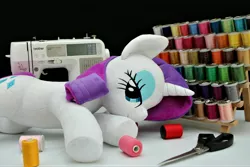 Size: 4096x2730 | Tagged: safe, artist:azurier, derpibooru import, rarity, pony, unicorn, fabric, female, irl, lidded eyes, looking at you, lying down, mare, photo, plushie, scissors, sewing machine, smiling, solo