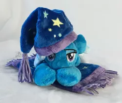 Size: 1781x1500 | Tagged: safe, artist:hollyivydesigns, derpibooru import, trixie, pony, unicorn, beanie (plushie), blanket, female, hat, irl, lidded eyes, mare, nightcap, photo, plushie, prone, sleepy, solo, trixie's nightcap