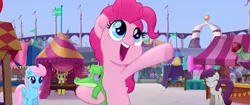 Size: 1920x804 | Tagged: safe, derpibooru import, screencap, gummy, peachy sweet, pinkie pie, unnamed character, unnamed pony, wind whistler (g4), alligator, earth pony, pegasus, pony, my little pony: the movie, apple family member, background pony, canterlot, cute, diapinkes, female, happy, hug, mare, market, open mouth, singing, smiling, tent, unamused, we got this together, youtube link