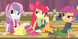 Size: 2462x1245 | Tagged: safe, derpibooru import, screencap, apple bloom, photo finish, scootaloo, snails, snips, sweetie belle, equestria girls, rainbow rocks, angry, apple bloom's bow, boots, bow, clothes, crossed legs, cutie mark crusaders, female, hair bow, jacket, looking at something, shirt, shoes, shorts, sitting, skirt, stage, trio, trio female