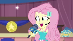 Size: 1280x720 | Tagged: safe, derpibooru import, screencap, fluttershy, best in show: the victory lap, equestria girls, equestria girls series, spoiler:eqg series (season 2), armpits, best in show logo, clothes, dress, earpiece, fluttershy boho dress, geode of fauna, hairpin, hand on hip, image, jewelry, magical geodes, microphone, necklace, open mouth, open smile, pink eyeshadow, png, sleeveless, smiling, solo
