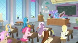 Size: 1600x898 | Tagged: safe, derpibooru import, screencap, bifröst, dawnlighter, gallus, goldy wings, loganberry, strawberry scoop, summer breeze, trixie, gryphon, pony, a horse shoe-in, book, bored, chalk, chalkboard, classroom, clothes, desk, easel, female, friendship student, hat, hoof on cheek, inkwell, levitation, magic, male, mare, paper, quill, reading, school of friendship, scroll, teacher's desk, teenager, telekinesis, trash can, trixie's hat, vase, window