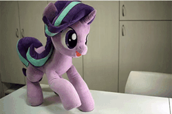 Size: 600x399 | Tagged: safe, artist:nekokevin, derpibooru import, starlight glimmer, pony, unicorn, series:nekokevin's glimmy, animated, chair, clapping, cute, excited, female, gif, glimmerbetes, happy, hoofy-kicks, irl, looking at you, lying down, mare, open mouth, photo, plushie, raised hoof, silly, silly pony, sitting, smiling, solo, stop motion, table, underhoof, weapons-grade cute