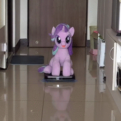 Size: 640x640 | Tagged: safe, artist:nekokevin, derpibooru import, starlight glimmer, pony, unicorn, series:nekokevin's glimmy, animated, behaving like a cat, female, happy, irl, it's coming right at us, looking at you, mare, open mouth, photo, plushie, riding, roomba, sitting, solo, sound, underhoof, webm