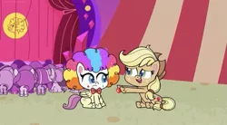 Size: 827x458 | Tagged: safe, derpibooru import, screencap, applejack, fluttershy, earth pony, pegasus, pony, my little pony: pony life, spoiler:pony life s02e19, applejack's hat, bowtie, circus tent, clown makeup, clown nose, clown wig, cowboy hat, duo, duo female, female, flutterclown, hat, image, jpeg, lolly-pop, open mouth, sitting, stage