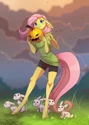 Size: 1897x2676 | Tagged: safe, artist:1an1, derpibooru import, fluttershy, anthro, bird, pegasus, rabbit, unguligrade anthro, androgynous, animal, beautiful, blue eyes, blushing, bunny ears, clothes, cloud, compression shorts, cute, evening, female, floppy ears, grass, halloween, holiday, hoodie, image, jack-o-lantern, looking at you, pink mane, pink tail, png, pumpkin, shorts, shyabetes, standing, sweater, wavy mouth, yellow fur
