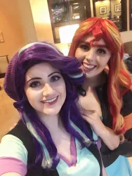 Size: 722x960 | Tagged: safe, artist:maddymoiselle, artist:sarahndipity cosplay, derpibooru import, starlight glimmer, sunset shimmer, human, beanie, clothes, cosplay, costume, duo, everfree northwest, everfree northwest 2019, hat, image, irl, irl human, jpeg, looking at you, photo, smiling, smiling at you