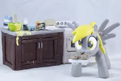 Size: 3860x2574 | Tagged: safe, artist:azgchip, derpibooru import, derpy hooves, pegasus, pony, baking, batter, cabinet, counter top, craft, cute, egg carton, female, flour, food, image, looking at you, mare, milk bottle, mouth hold, muffin, muffin tray, oven, photo, png, salt, sculpture, solo, spread wings, stove, wall eyed, wax, wings, wooden spoon