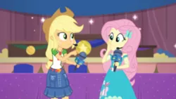 Size: 3410x1920 | Tagged: safe, derpibooru import, screencap, applejack, fluttershy, best in show: the victory lap, equestria girls, equestria girls series, spoiler:eqg series (season 2), applejack's hat, belt, blurry, clothes, cowboy hat, cutie mark, cutie mark on clothes, denim skirt, female, geode of fauna, geode of super strength, hairpin, hat, image, jewelry, jpeg, magical geodes, microphone, necklace, skirt