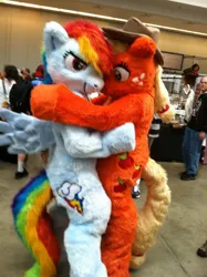 Size: 638x854 | Tagged: safe, artist:spainfischer, derpibooru import, applejack, rainbow dash, anthro, earth pony, human, pegasus, pony, 2011, clothes, convention, cosplay, costume, cowboy hat, cutie mark, duo, embrace, fursuit, hat, hug, image, irl, irl human, jpeg, photo, ponysuit, smiling, smirk, tail, wings