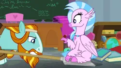 Size: 1920x1080 | Tagged: safe, derpibooru import, screencap, rockhoof, silverstream, classical hippogriff, earth pony, hippogriff, pony, a rockhoof and a hard place, season 8, spoiler:s08, chalkboard, classroom, colored hooves, desk, duo, female, image, jewelry, male, mare, necklace, png, rockhoof's shovel, shovel, sittin on shovel, sitting, stallion