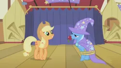 Size: 1000x563 | Tagged: safe, derpibooru import, edit, edited screencap, screencap, applejack, trixie, earth pony, pony, unicorn, boast busters, season 1, alternate scenario, apple, cape, clothes, duo, duo female, female, food, frown, gem, grin, hat, image, looking at someone, mare, png, rope, silly, smiling, stage, stars, tied up, trixie is not amused, trixie's cape, trixie's hat, unamused