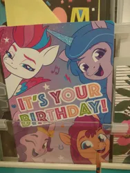 Size: 3000x4000 | Tagged: safe, derpibooru import, izzy moonbow, pipp petals, sunny starscout, zipp storm, earth pony, pegasus, pony, unicorn, g5, my little pony: a new generation, my little pony: tell your tale, 2023, birthday, birthday card, blue eyes, crown, cyan eyes, eyebrows, female, green eyes, happy birthday, horseshoes, image, irl, jewelry, jpeg, lightning, looking at you, mare, music notes, photo, purple eyes, regalia, royal sisters (g5), safeway, siblings, sisters, smiling, smiling at you, starry eyes, stars, store, text, turquoise eyes, wingding eyes