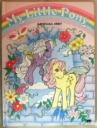 Size: 356x468 | Tagged: safe, derpibooru import, official, rosedust, butterfly, flutter pony, insect, pony, g1, book, book cover, cloud, cover, cover art, duo, duo female, female, flower, flying, forget-me-not, image, jpeg, mare, my little pony annual 1987, my little pony logo, photo, spread wings, tail, underhoof, vine, wings