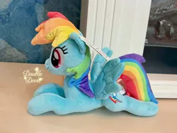 Size: 4062x3046 | Tagged: safe, derpibooru import, official, rainbow dash, pegasus, pony, g4, image, irl, jpeg, lying down, merchandise, photo, plushie, pony plushie, reesee, side view, smiling, solo, spread wings, text, wings