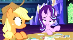 Size: 1394x783 | Tagged: safe, derpibooru import, screencap, applejack, starlight glimmer, pony, every little thing she does, duo, female, image, library, lidded eyes, mare, photos, png, shrunken pupils, table, twilight's castle, twilight's castle library