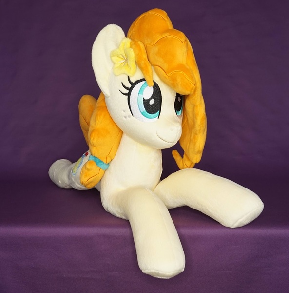 Size: 1296x1312 | Tagged: safe, artist:egalgay, derpibooru import, pear butter, earth pony, pony, female, flower, flower in hair, happy, image, irl, jpeg, lying down, mare, photo, plushie, prone, smiling, solo