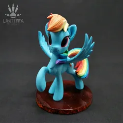 Size: 2560x2560 | Tagged: safe, alternate angle, alternate version, artist:lakterra, derpibooru import, rainbow dash, pegasus, pony, craft, female, figurine, g4, image, irl, jpeg, looking up, mare, photo, polymer clay, raised hoof, signature, smiling, solo, spread wings, stand, tail, wings