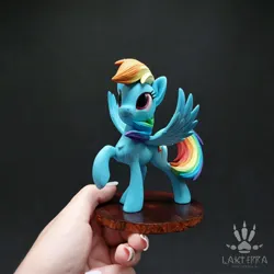 Size: 2560x2560 | Tagged: safe, alternate angle, alternate version, artist:lakterra, derpibooru import, rainbow dash, human, pegasus, pony, craft, female, figurine, g4, hand, holding a pony, image, irl, jpeg, looking up, mare, photo, polymer clay, raised hoof, signature, smiling, solo, spread wings, stand, tail, wings