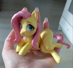 Size: 1125x1044 | Tagged: safe, artist:emysdraw, derpibooru import, fluttershy, pegasus, pony, craft, female, hand, holding a pony, image, irl, jpeg, lying down, mare, photo, sculpture, side, solo