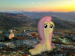 Size: 1200x900 | Tagged: safe, derpibooru import, fluttershy, pegasus, pony, g4, floppy ears, folded wings, gritted teeth, image, irl, looking up, mountain, mountain range, nature, photo, png, ponies in real life, sitting, smiling, sundown, wings