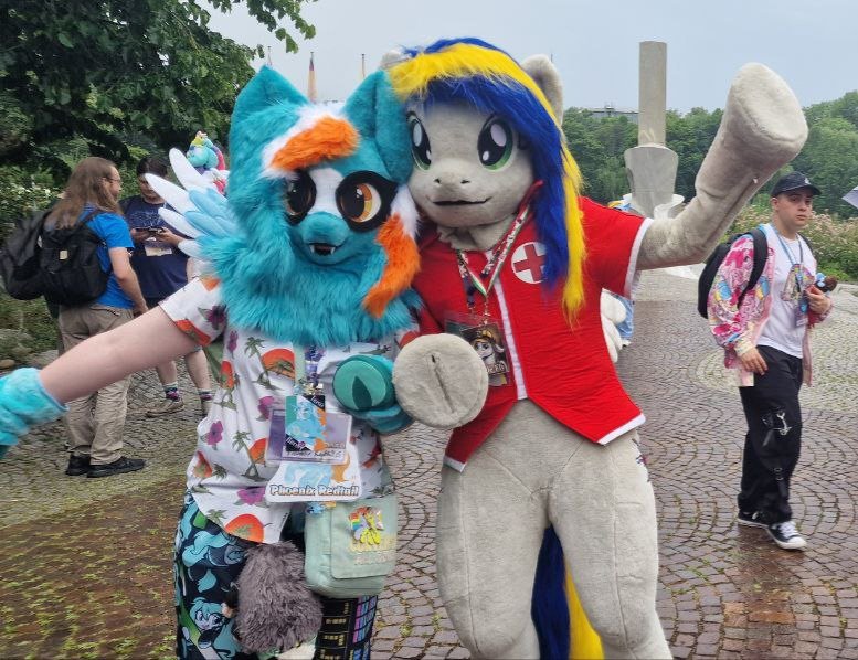 Size: 777x598 | Tagged: safe, artist:atalonthedeer, artist:eaglefly_, derpibooru import, oc, oc:eagle fly, oc:phoenix redtail, 2024, badge, convention, duo focus, fursuit, galacon, image, irl, jpeg, outdoors, photo, ponysuit