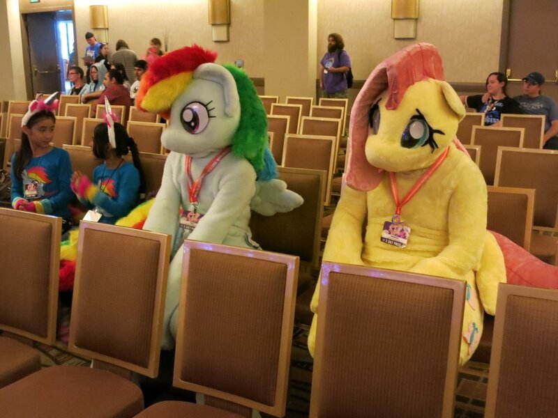 Size: 1241x931 | Tagged: safe, artist:koowan, artist:stinken1, derpibooru import, fluttershy, rainbow dash, human, pegasus, convention, duo focus, fursuit, image, irl, irl human, jpeg, multiple characters, photo, ponysuit, sitting