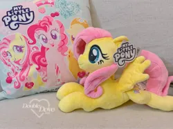 Size: 3363x2522 | Tagged: safe, derpibooru import, official, applejack, fluttershy, pinkie pie, pegasus, pony, g4, couch, double dove, image, irl, jpeg, looking at you, lying down, merchandise, open mouth, open smile, photo, pillow, plushie, pony plushie, reesee, smiling, smiling at you, text